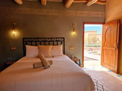 a bed with a teddy bear sitting on top of it at Maison d'hôtes Tigminou - Adults Only in Aït Ben Haddou