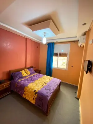 a bedroom with a bed with a purple comforter at Hotel Achokre in Oulad Yaïch