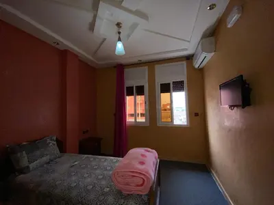 a bedroom with a bed with a pink sheet on it at Hotel Achokre in Oulad Yaïch