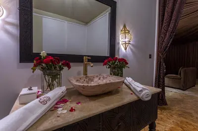 a bathroom with a stone sink and flowers on a counter at LEMNAOUAR ERG CAMP in Merzouga