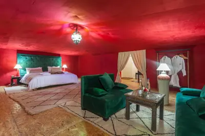 a red bedroom with a bed and a green chair at LEMNAOUAR ERG CAMP in Merzouga