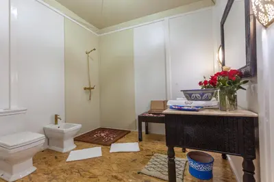 a bathroom with a toilet and a vase of flowers on a table at LEMNAOUAR ERG CAMP in Merzouga