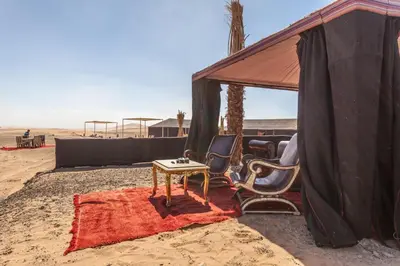 a tent with a table and chairs in the desert at LEMNAOUAR ERG CAMP in Merzouga