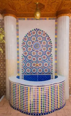 a fountain in a room with a tile wall at Riad Mahrez in Fès