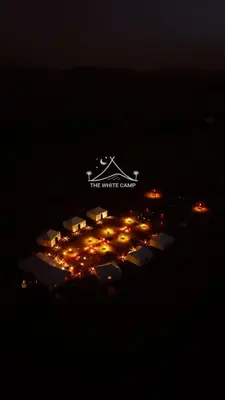 a white center lit up at night with lights at The White Camp Merzouga - Official Luxury Desert Camp & Camel Tours in Merzouga