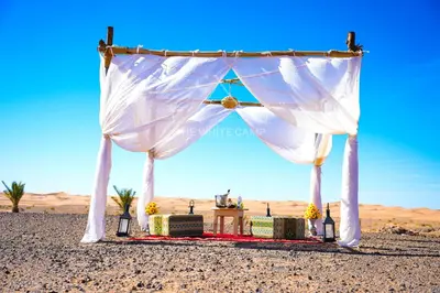 a wedding arch in the desert with a table and candles at The White Camp Merzouga - Official Luxury Desert Camp & Camel Tours in Merzouga