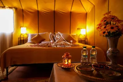 a bedroom with a bed and a table with two bottles of water at The White Camp Merzouga - Official Luxury Desert Camp & Camel Tours in Merzouga