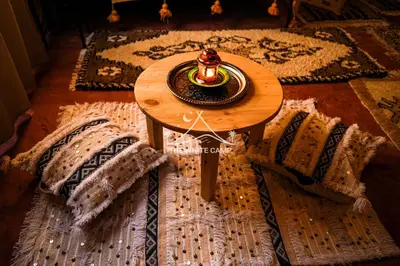 a table with a candle on top of a rug at The White Camp Merzouga - Official Luxury Desert Camp & Camel Tours in Merzouga