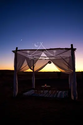 a tent with a table in the middle of a field at The White Camp Merzouga - Official Luxury Desert Camp & Camel Tours in Merzouga