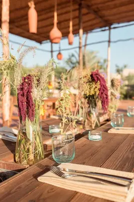 a wooden table with vases of flowers on it at Bakkal Farm Agrolodge in Marrakech