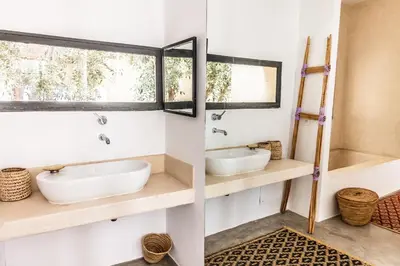 a bathroom with two sinks and two mirrors at Bakkal Farm Agrolodge in Marrakech