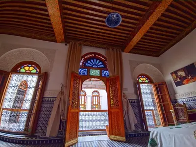 a room with three arched doors and stained glass windows at Riad Fès Center in Fès