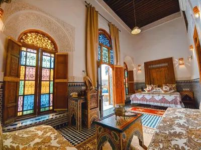 a bedroom with a bed and stained glass windows at Riad Fès Center in Fès