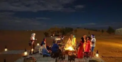 a group of people sitting on the beach at night at Merzouga Nice luxury Camp in Merzouga