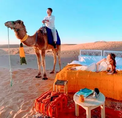 a man is riding a camel in the desert at Merzouga Nice luxury Camp in Merzouga