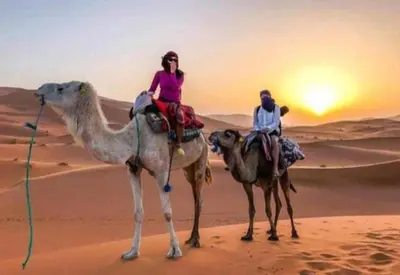 two people riding on the camel in the desert at Merzouga Nice luxury Camp in Merzouga