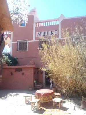 a building with a table and benches in front of it at Afoulki Ecotourism Guest House in Telouet