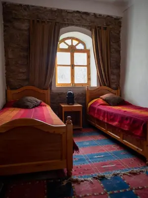 a bedroom with two beds and a window at Afoulki Ecotourism Guest House in Telouet