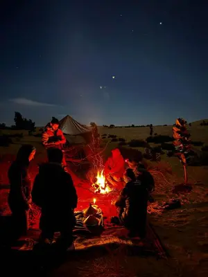 a group of people sitting around a camp fire at Mhamid Sahara Camp - Mhamid El Ghizlane in Mhamid
