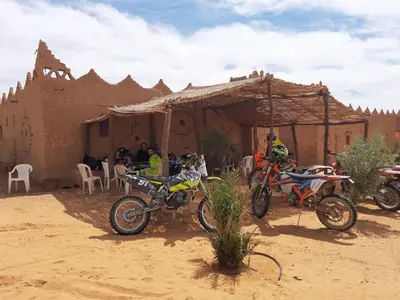 a group of motorcycles parked in the desert at Auberge Dinosaur Kem Kem in Tafraoute Sidi Ali