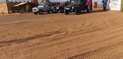 a couple of trucks parked on a dirt road at Auberge Dinosaur Kem Kem in Tafraoute Sidi Ali