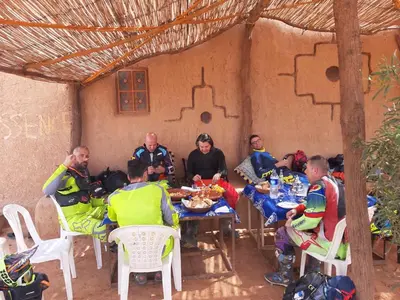 a group of people sitting at a table eating food at Auberge Dinosaur Kem Kem in Tafraoute Sidi Ali