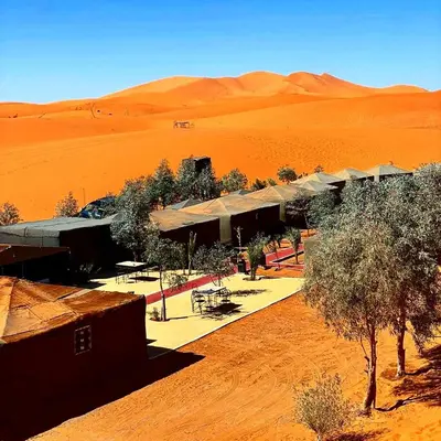 a group of buildings in the middle of a desert at Merzouga Camel Trekking Camp in Merzouga