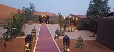a pathway with lights in front of a house at Merzouga Camel Trekking Camp in Merzouga