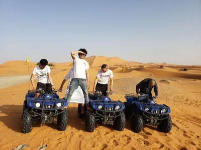a group of people standing on atvs in the desert at Merzouga Ana luxury Camp in Merzouga