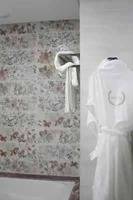 a white robe hanging on a wall with a floral wallpaper at Z Hotel Meknes in Meknès