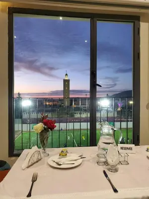 a dining table with a view of a clock tower at Eventi Club by cité des sports adarissa in Fès