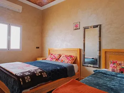 a bedroom with two beds and a mirror at Merzouga apartments holiday in Merzouga