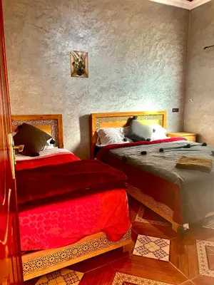 a bedroom with two beds with red sheets at Merzouga apartments holiday in Merzouga