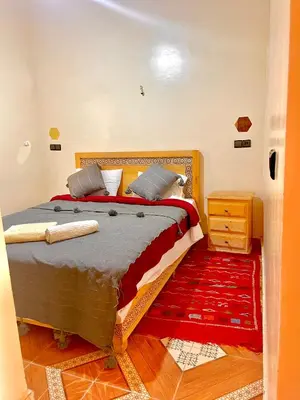 a bedroom with a large bed with a red rug at Merzouga apartments holiday in Merzouga