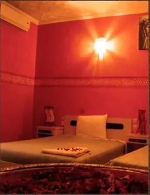 a bedroom with a bed with a light on the wall at Hotel Bab Sahara in Ouarzazate