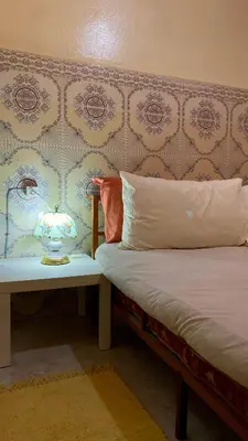 a bedroom with a bed with a headboard and a table at Dar Relax Hostel, Gorges de Todra in Tinerhir