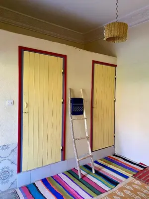 a room with two yellow doors and a ladder at Dar Relax Hostel, Gorges de Todra in Tinerhir