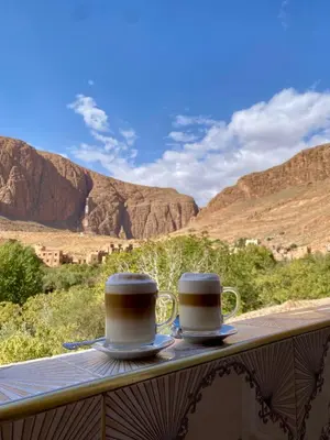 two cups of coffee sitting on a balcony with mountains at Dar Relax Hostel, Gorges de Todra in Tinerhir