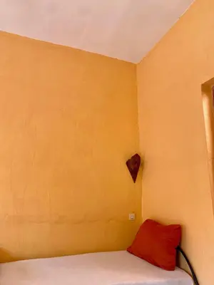 a bedroom with a red pillow and a yellow wall at Dar Relax Hostel, Gorges de Todra in Tinerhir