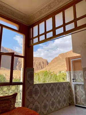 a bedroom with a view of the mountains through a window at Dar Relax Hostel, Gorges de Todra in Tinerhir
