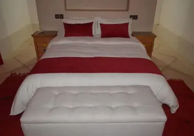 a bedroom with a large bed with red pillows at Kasr Tin Hinane in Merzouga