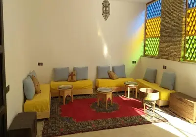 a living room with yellow couches and stained glass windows at Kasr Tin Hinane in Merzouga