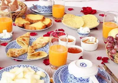 a table with plates of food and glasses of orange juice at Kasr Tin Hinane in Merzouga