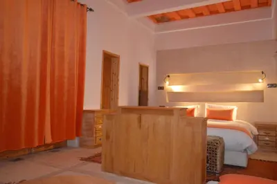a bedroom with a bed and a wooden dresser at Kasr Tin Hinane in Merzouga