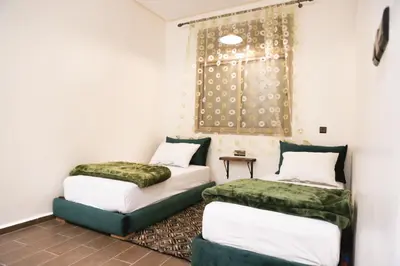 two beds in a room with a window at Issli appartment climatisé hiver et été in Azrou