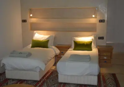 a bedroom with two beds with green pillows at Riad Tin Hinane in Merzouga