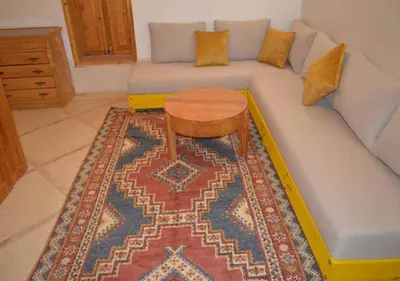 a living room with a blue couch with a wooden table at Riad Tin Hinane in Merzouga