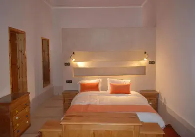 a bedroom with a large bed with orange pillows at Riad Tin Hinane in Merzouga