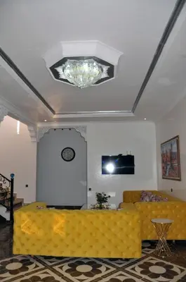 a living room with a yellow couch and a chandelier at Jolie villa moderne avec piscine privée. in Marrakech
