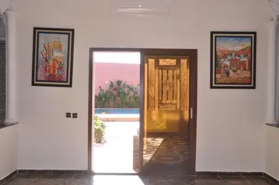 a hallway with a door and paintings on the wall at Jolie villa moderne avec piscine privée. in Marrakech